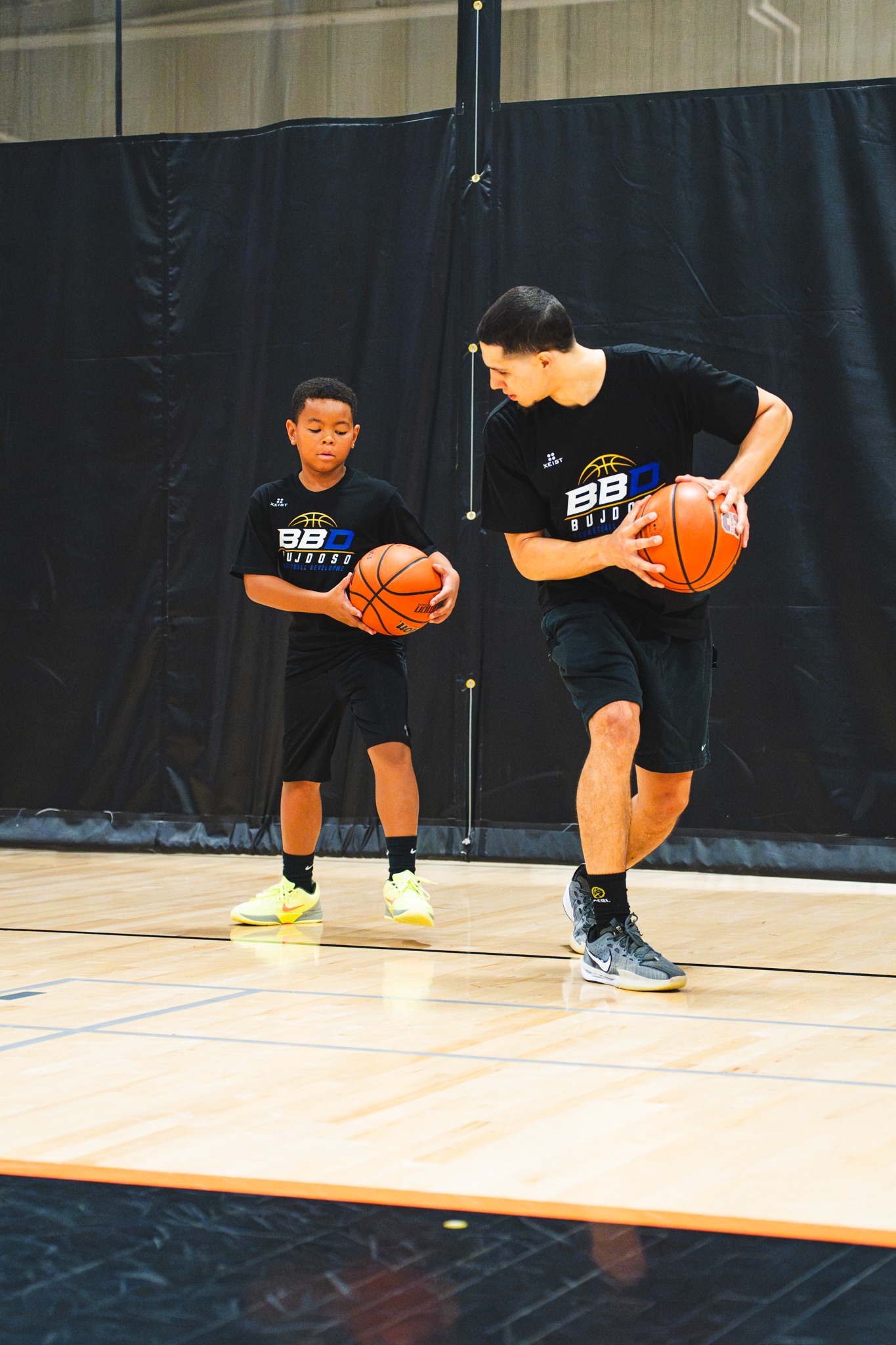 BBD coach demonstrating ball-handling footwork with a junior player